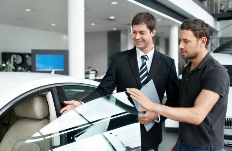 Two people talking at a vehicle dealership